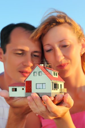 Young woman and man keeping in hands model of house