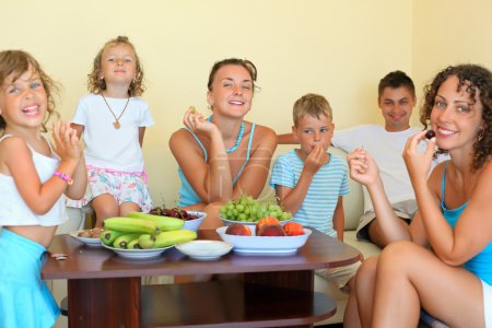 Big happy family with children eats fruit in cosy room