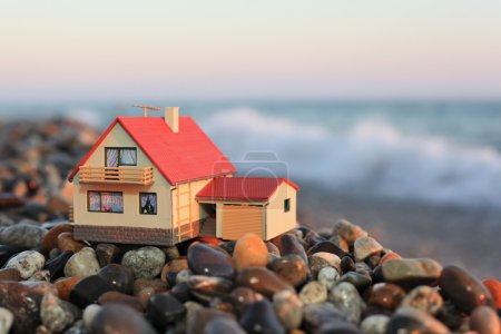 Model of house with garage on stony beach in evening