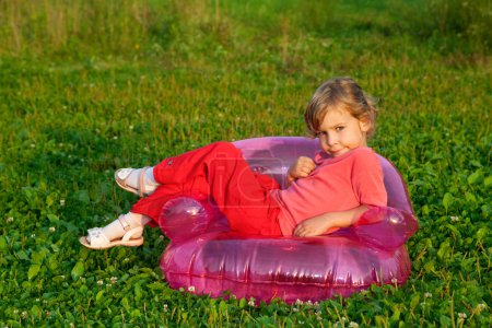Young model sits in inflatable armchair outdoors