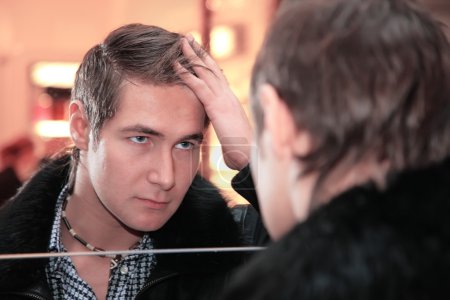 Young man looks in mirror