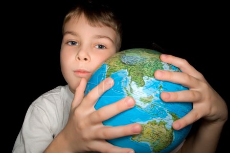 Boy embracing globe of world isolated on black background