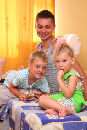 Children with father sitting on bed in room