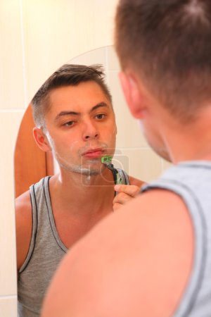 Man shaves befor mirror