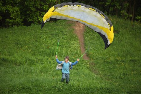 Boy runs from hill with parachute