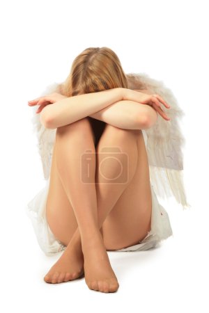 Girl in angel's costume sits face in knees and having closed by
