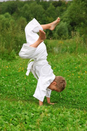 Karate boy does handstand on lawn
