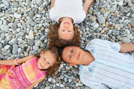 Happy family with little girl lying on stony beach, Concerning w