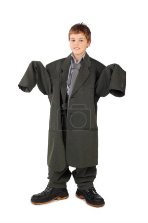 Little boy in big grey man's suit and boots standing isolated on
