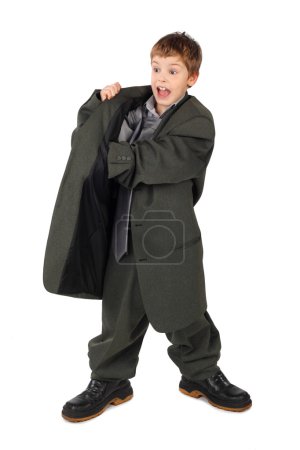 Little boy in big grey man's suit and boots hand in pocket isola