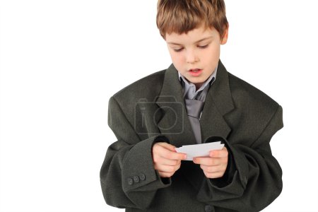Little boy in big grey man's suit looking at business card isol