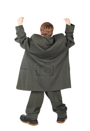Little boy in big grey man's suit and boots hand view from back