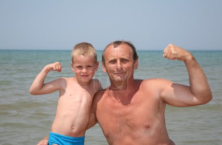 Grandfather and grandson show bicepses
