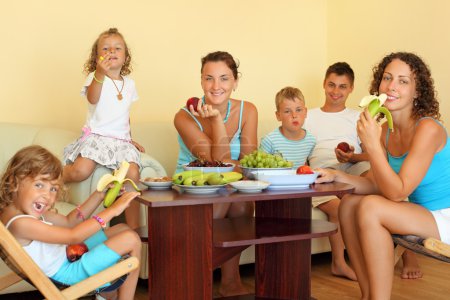 Big happy family with children eats fruit in cosy room