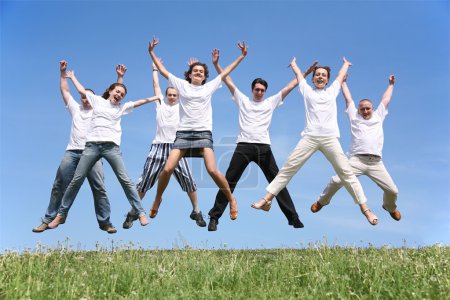 Seven friends in white T-shorts swing hands in a jump
