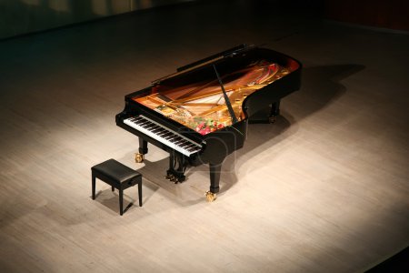 Piano with bouquet of flowers on scene in concert hall
