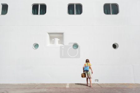 Little girl looking down near large white passenger liner at do