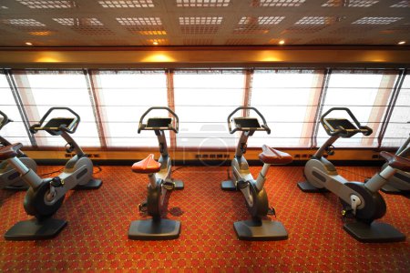 Large gym hall with exercise bicycle near window in cruise ship