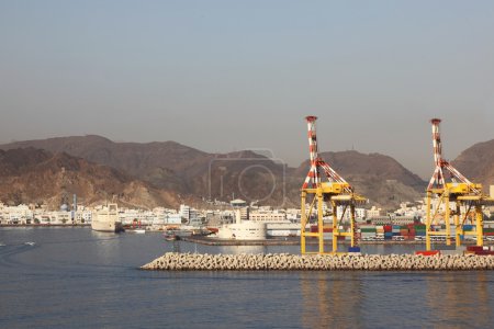 Two yellow cranes in shipping port near mountains summer day