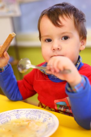 Little boy eats in kindergarten
