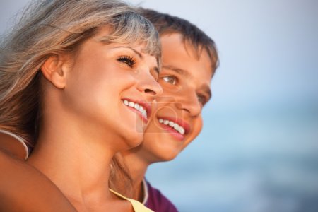 Smiling boy and young woman on beach in evening, Looking afar