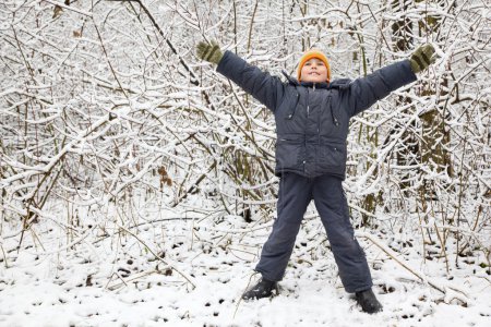 Boy lifted hands upwards in wood in winter