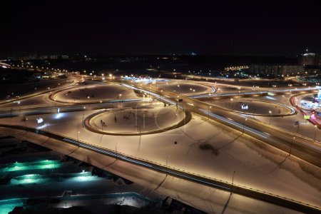 Night winter cityscape with big interchange, lighting columns an