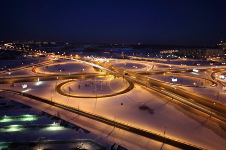 Night winter cityscape with big interchange, lighting columns an