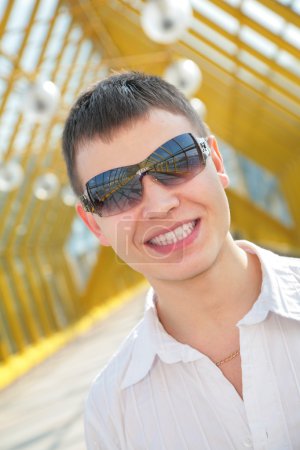 Young smiling man in sunglasses on footbridge