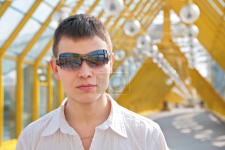Young man in sunglasses on footbridge