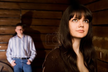 Beautiful woman brunette and young man in wooden log hut