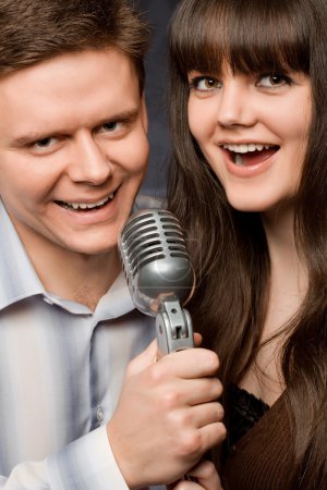 Young beautiful woman and smiling man sing in microphone