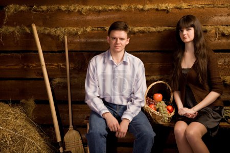 Young man and woman near basket of fruit sitting on bench