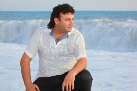 One man is sitting near water on sea coast