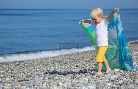 Child with shawl goes on pebble beach