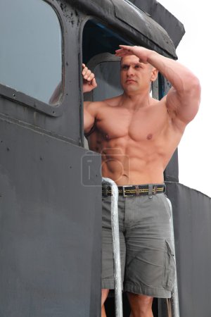 Strong shirtless man keeps watch on locomotive