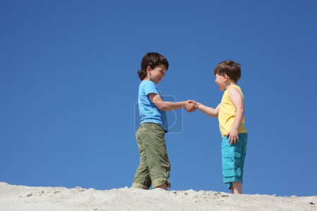 Two boys greet on sand