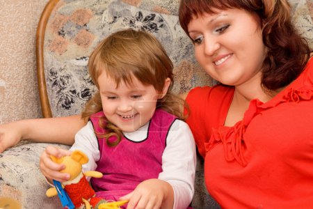 Little girl and woman play a toy in a cosy room