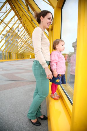 Young woman with baby on pedestrain bridge