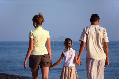 Family with girl walks along sea beach