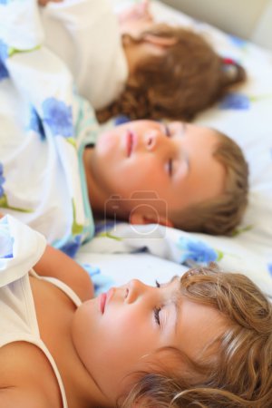 Children three together sleeping on bed in cosy room, lying on b