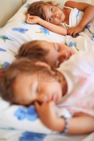 Children three together sleeping on bed in cosy room, focus on g