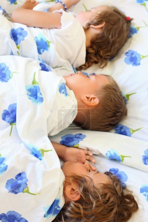 Children three together sleeping on bed in cosy room