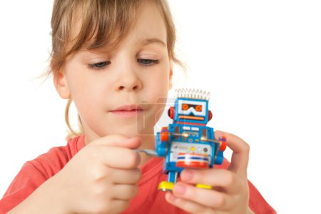 Pretty little girl in red T-shirt plays with clockwork robot iso