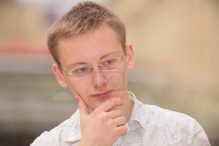 Thinking young man in glasses