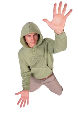 Man in jacket with hood is kneeling and has rised hand