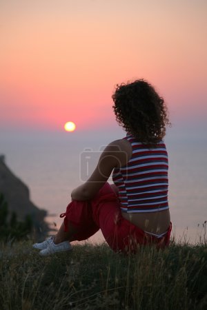 The woman looks at a sunset