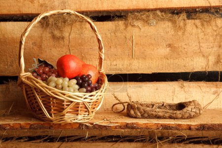 Rural still life. Basket of grapes and apples, and bast shoes on