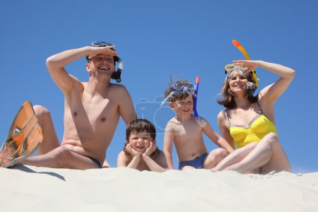 Family with son lying on sand with snorkeling masks