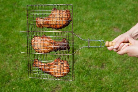 Hands hold a lattice with fried meat